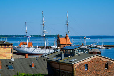 Sailboats moored at harbor against clear blue sky