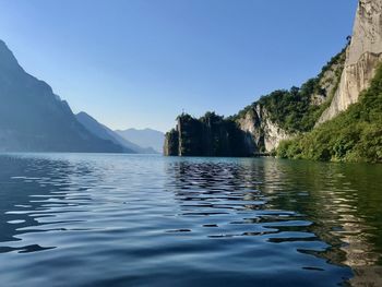 Scenic view of lake and mountains against clear blue sky