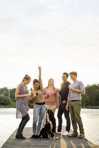 Rear view of people with dog standing against sky