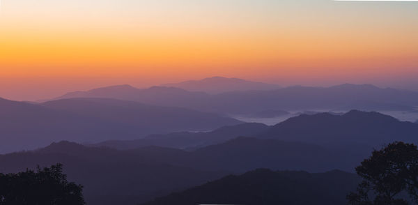 Scenic view of silhouette mountains against orange sky