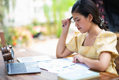 Young woman using mobile phone while sitting on table