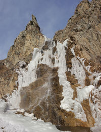 Low angle view of rock formation against sky during winter