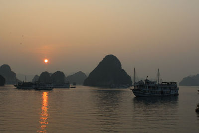 Boats on halong bay by rock formations against clear sky