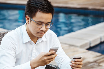 Young man using mobile phone in swimming pool
