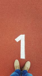 Low section of person standing by number 1 on running track