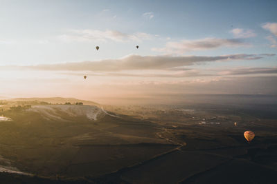 Hot air balloons flying over landscape against sky