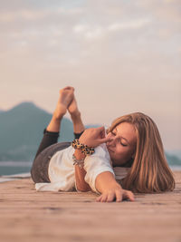 Portrait of woman lying on beach against sky during sunset