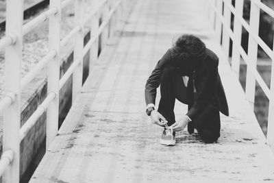 Businessman tying shoelace on footbridge