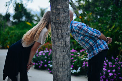 Rear view of people standing by tree trunk