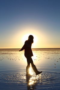 Silhouette man on beach against sky during sunset