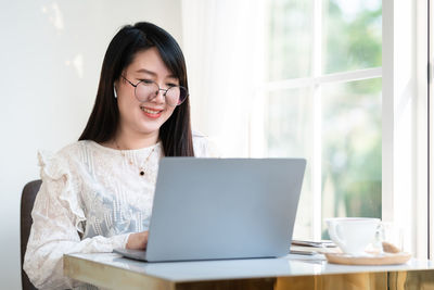 Young woman using mobile phone while sitting on table