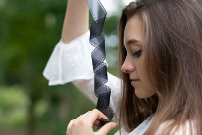 Close-up of young woman holding film reel outdoors