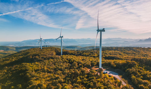 View of a wind farm in a mountainous forest field with mountains in the background