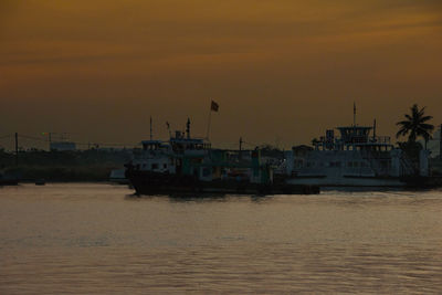 Trawlers moored at harbor during sunset