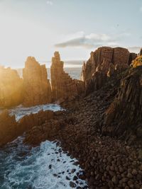 Rock formations on beach against sky