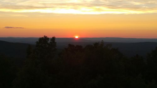 Scenic view of silhouette mountains against orange sky