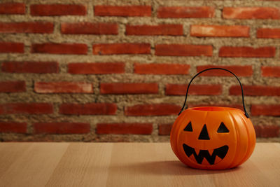 Close-up of pumpkin on table against brick wall during halloween