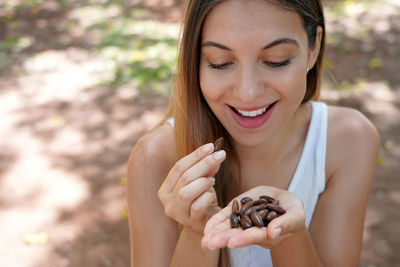 Beautiful healthy girl eating baru nut seeds outdoor. looks at baru seeds in her hand.