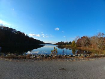 Reflection of trees in water against blue sky