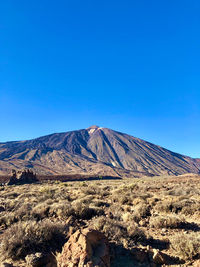 Scenic view of arid landscape against clear blue sky