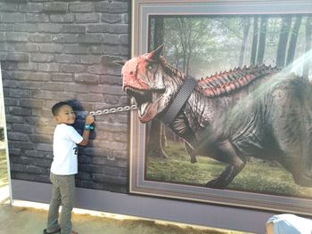 Full length of boy standing against wall