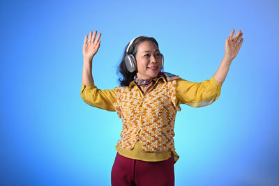 Portrait of young woman standing against blue sky