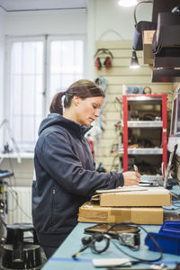 Side view of mature woman working in computer store