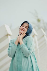 Portrait of young woman standing against wall