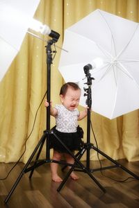 Full length of baby girl crying while standing in photo studio