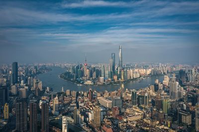 Aerial view of buildings in city against cloudy sky