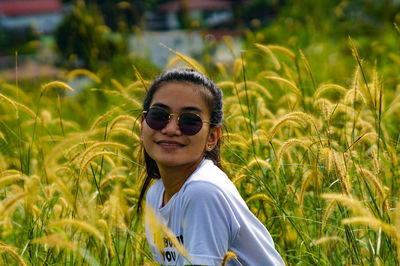 Portrait of smiling young woman wearing sunglasses on field