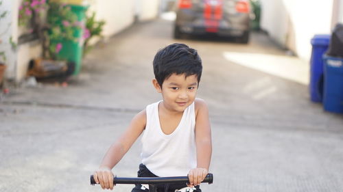 Portrait of cute boy sitting on bicycle outdoors