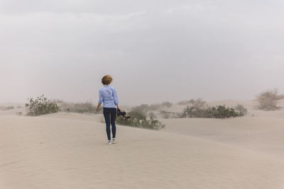 Rear view of man walking on landscape against sky