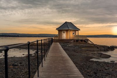 Pier over sea against sky during sunset