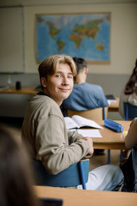 Portrait of teenage boy sitting on chair in classroom