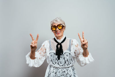 Portrait of young woman with arms crossed standing against white background