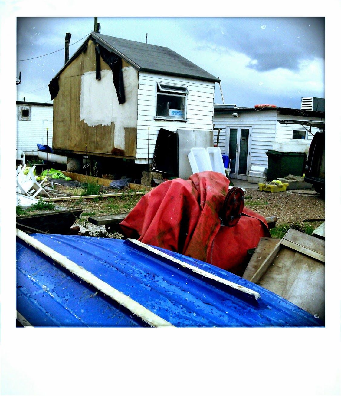 Travels with my mobile camera phone bawdsea felixstowe fishing village fishing boats boats fish hut buildings local people tourist sun se jetty clouds grass documentary reportage photography photographic colour color camera phone fone man with shades seat