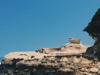 Scenic view of rock formations at beach against sky