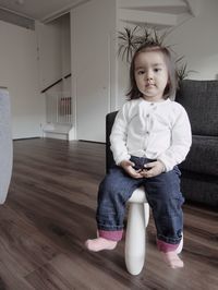 Portrait of cute girl sitting on hardwood floor at home