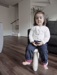 Portrait of cute girl sitting on chair at home