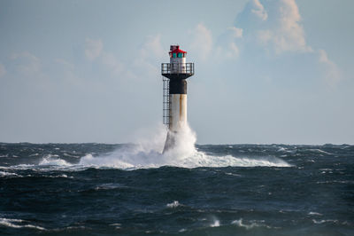 Lighthouse by sea against sky