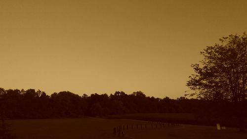 Silhouette trees on landscape against clear sky