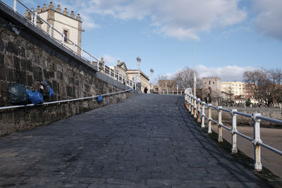 Rear view of woman walking on footbridge against sky