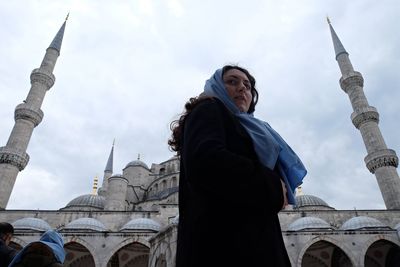 Low angle view of woman standing by mosque