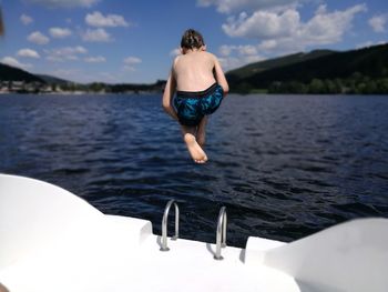 Rear view of shirtless boy jumping in sea