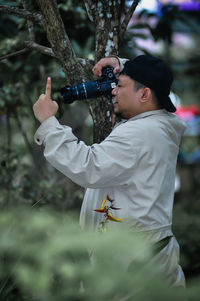 Side view of young man with arms raised standing outdoors