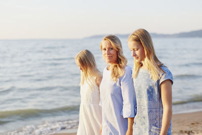 Rear view of women standing at beach against sky