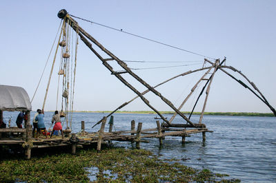 Fishermen fishing at sea shore against sky