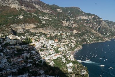 Aerial view of city by sea and mountains against clear sky