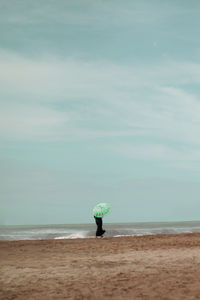 Rear view of man standing on beach against sky